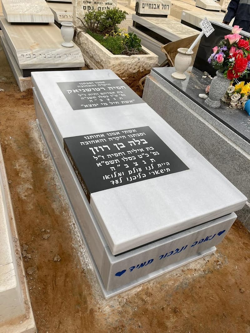 מצבה לבנה עם לוחות כיתוב שחורים